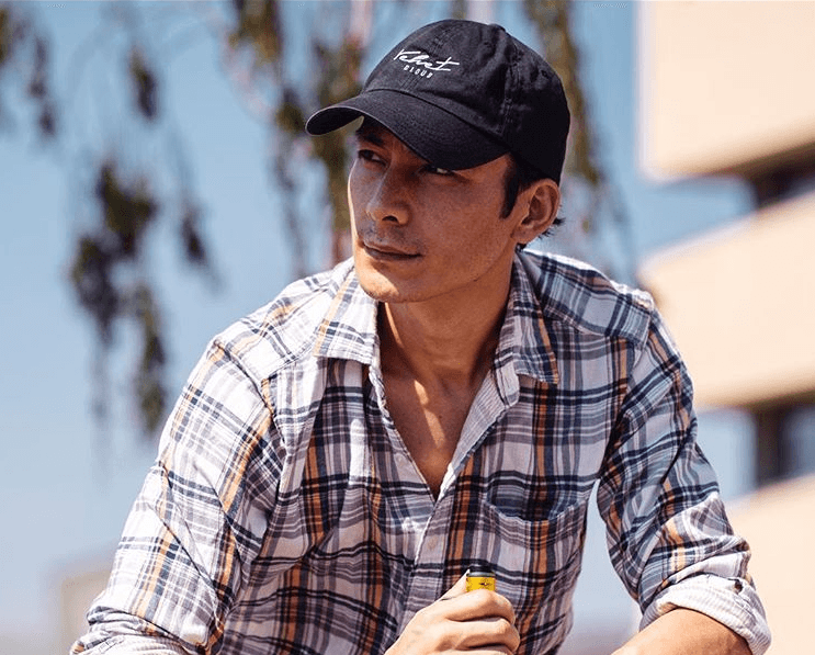 man wearing a Velvet Cloud hat holding an e-cigarette