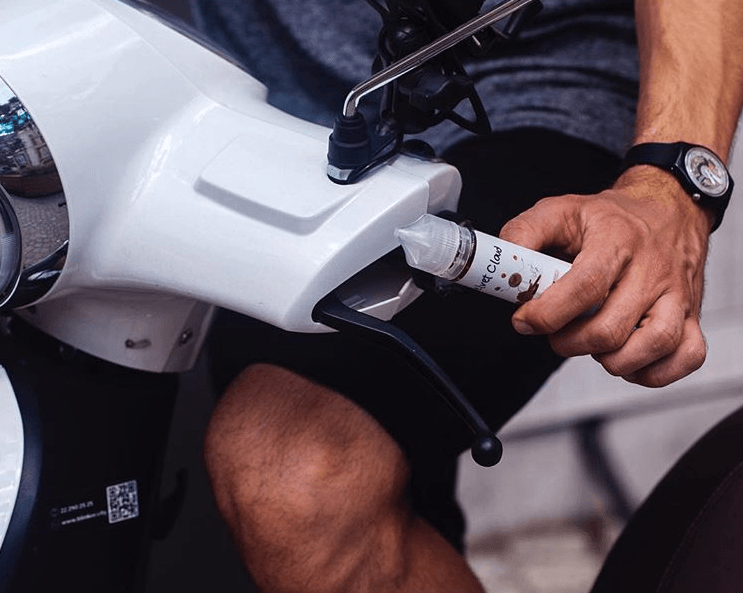 a man on a motorcycle holding a bottle of Velvet Cloud e-liquid
