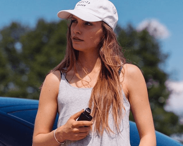 woman leaning against a car holding a Vape Mod