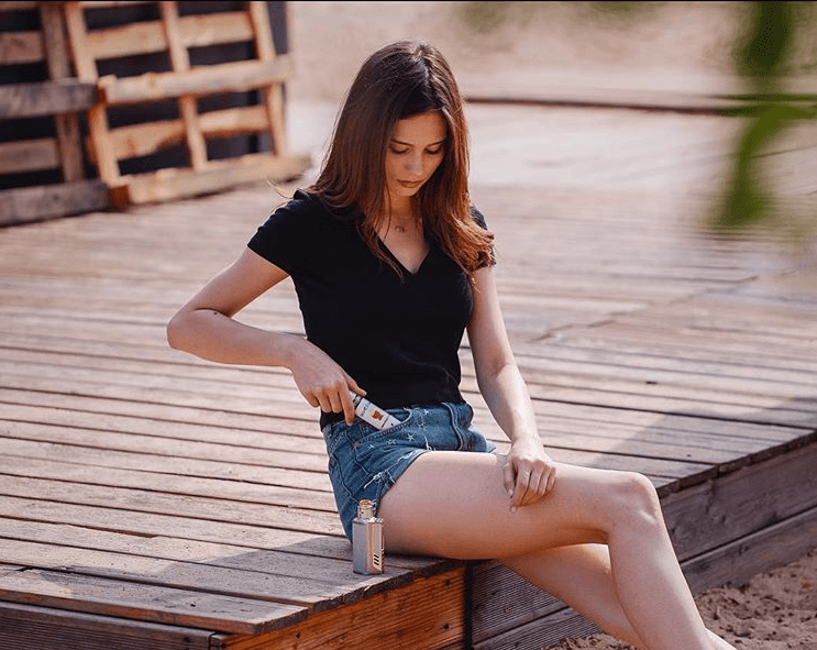 a woman pulling a bottle of Velvet Cloud high-quality e-liquid from her shorts pocket