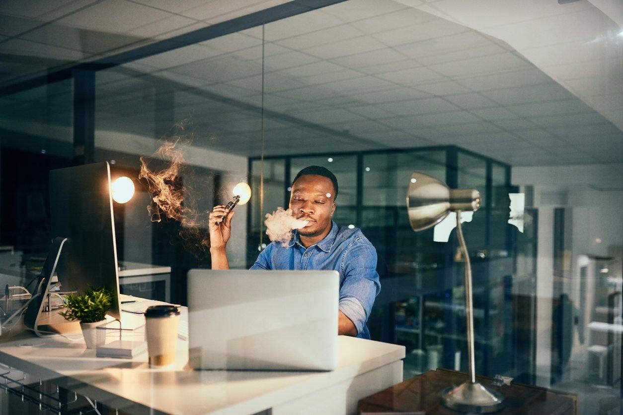man vaping in office at desk