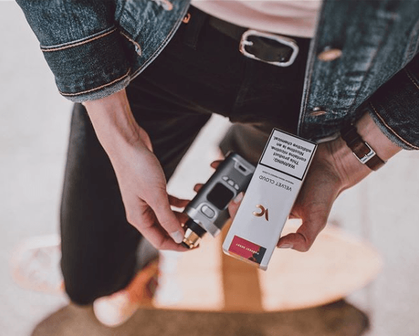 woman holding vape liquid and vape pen