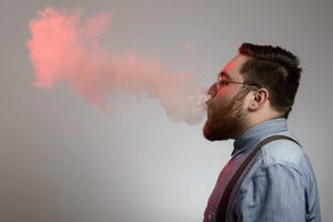 profile view of man exhaling red vape cloud