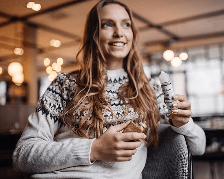 a first-time vaper holding a vape mod in one hand and velvet cloud e-liquid in the other