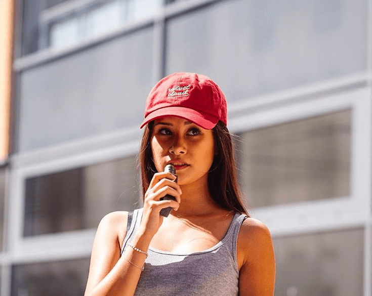 a woman wearing a Velvet Cloud hat and vaping unflavored e-liquid