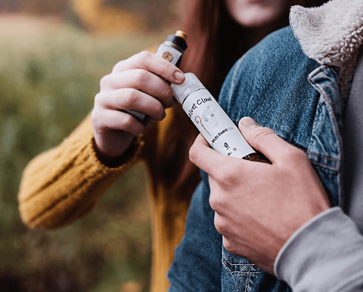 a picture of a man handing his female friend a bottle of Velvet Cloud e-liquid