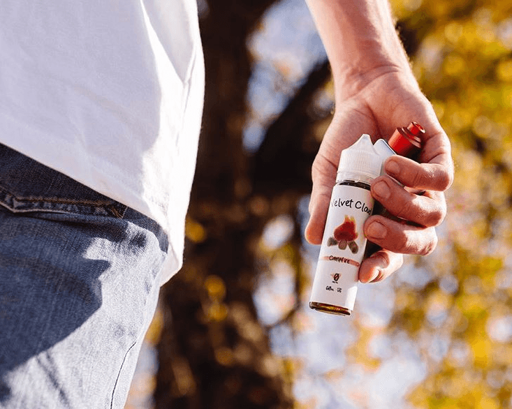 a close-up photo of man holding a bottle of Campfire e-liquid from Velvet Cloud