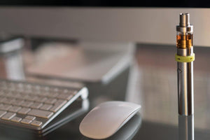 e-cigarette on desk next to mouse and keyboard