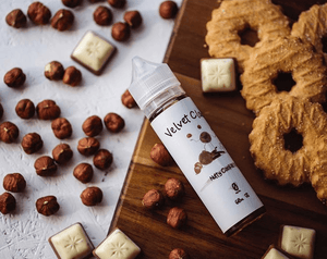Velvet Cloud's nutty cookie e-liquid on a table surrounded by cookies and hazelnuts