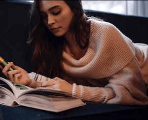 woman reading book on couch and vaping