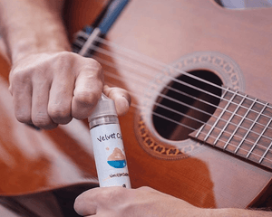 a man holding a guitar and a bottle of Velvet Cloud's vanilla custard e-liquid