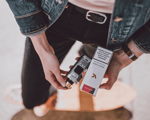 woman holding vape liquid and vape pen