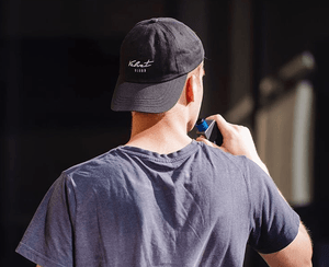 a shot of a man in a Velvet Cloud hat taking a hit from his vaping mod