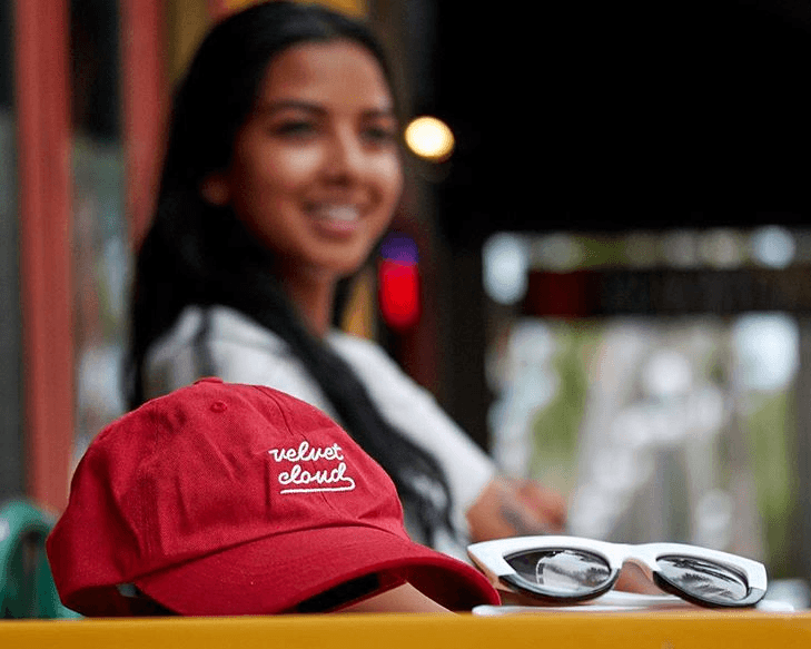a picture of a red Velvet Cloud hat in the foreground and a smiling girl in the background