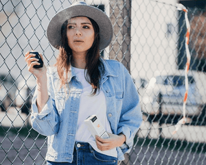 woman standing in front of fence vaping