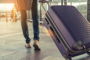 a woman pulling a purple suitcase behind her as she travels through the airport