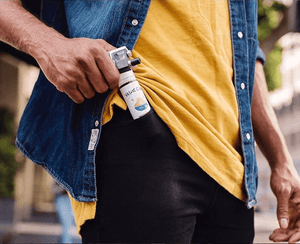 a man in a yellow shirt pulling a bottle of Velvet Cloud e-liquid from his jeans pockets