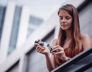 woman pouring a bottle of premium Velvet Cloud e-liquid into her mod tank